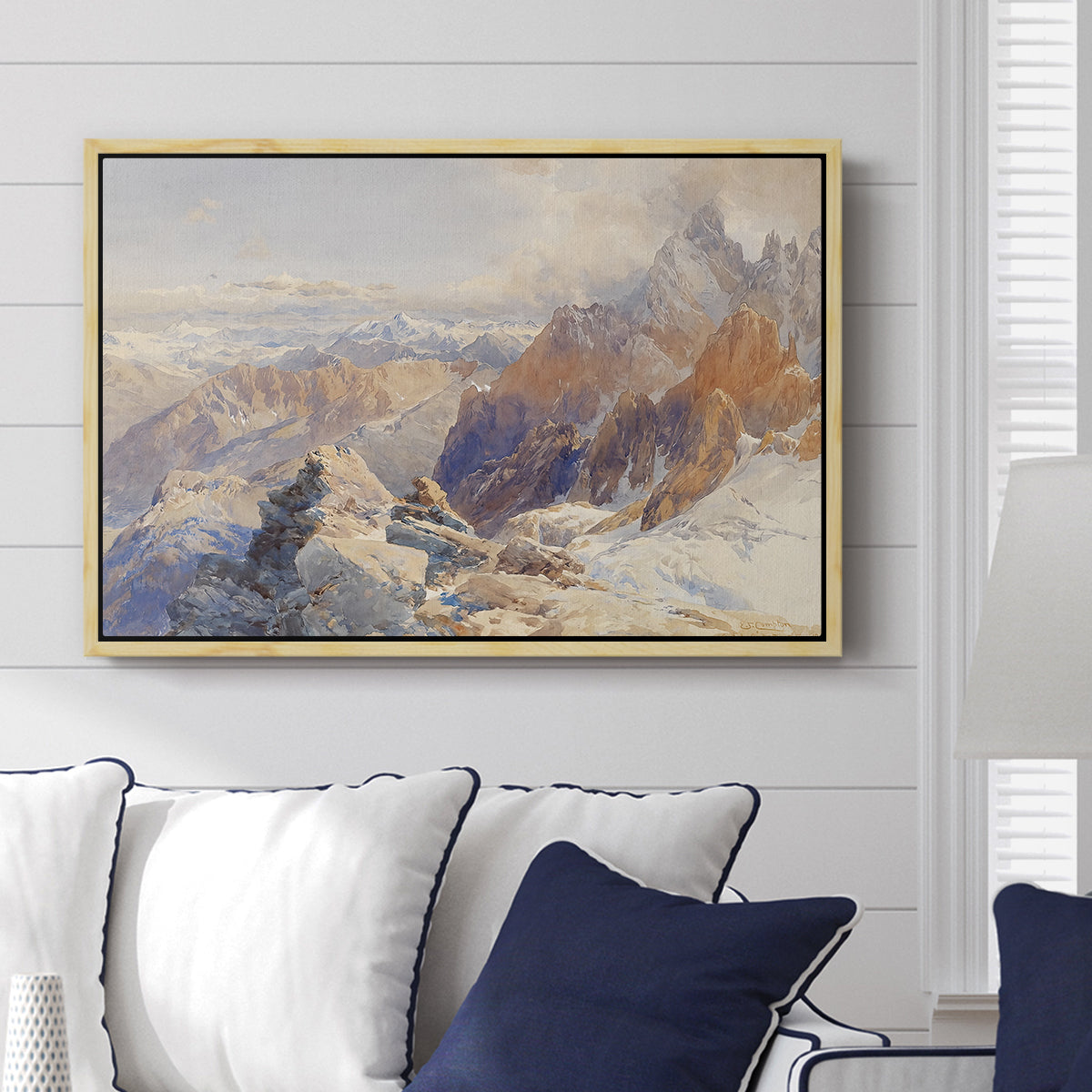 Col du Géant, 1903 by Edward Theodore Compton displayed above a sofa in a living room in a natural wood floater frame, featuring a high mountain landscape featuring dramatic ridges and glacier terrain.