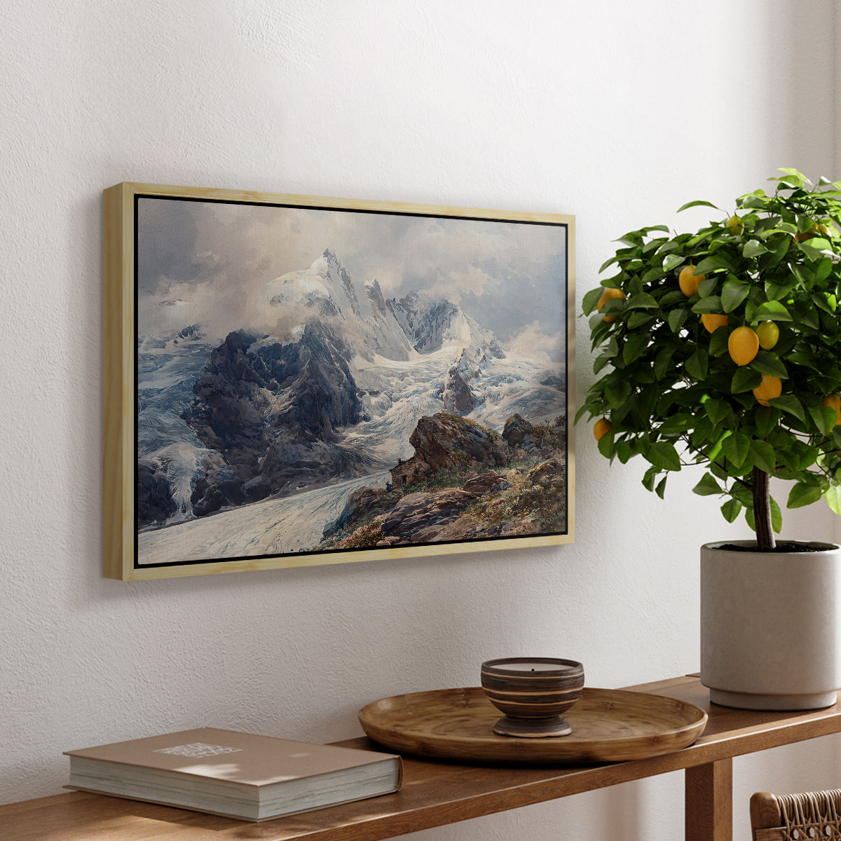 The Grossglockner, 1880 by Edward Theodore Compton, presented in a natural wood floater framed canvas featuring a towering mountain peak rising above rocky alpine landscape, displayed above a hallway console table.