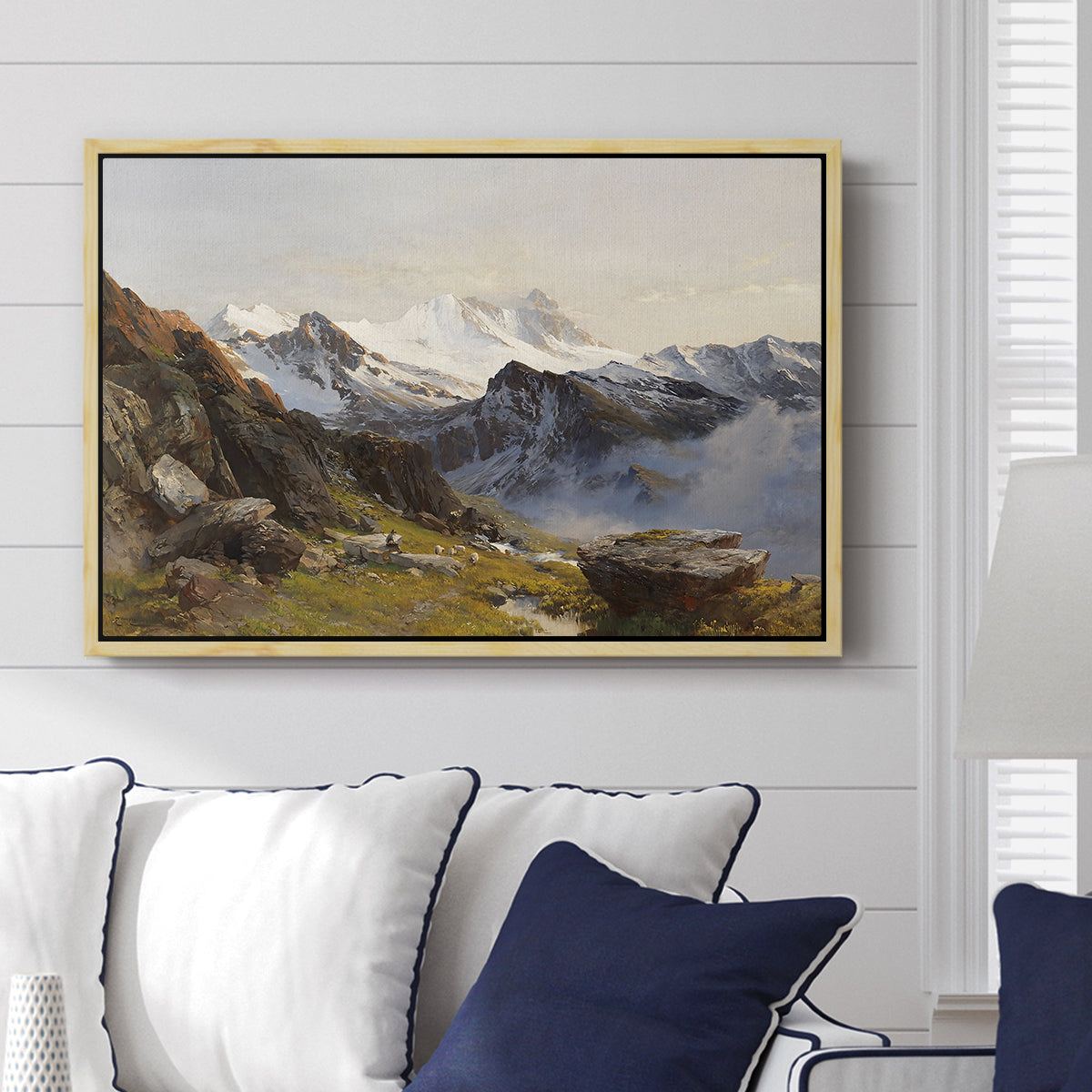 The Großglockner from the Prager Hut, 1890 by Edward Theodore Compton displayed above a sofa in a living room in a natural wood floater frame, featuring a mountain summit seen from elevated viewpoint with surrounding landscape.