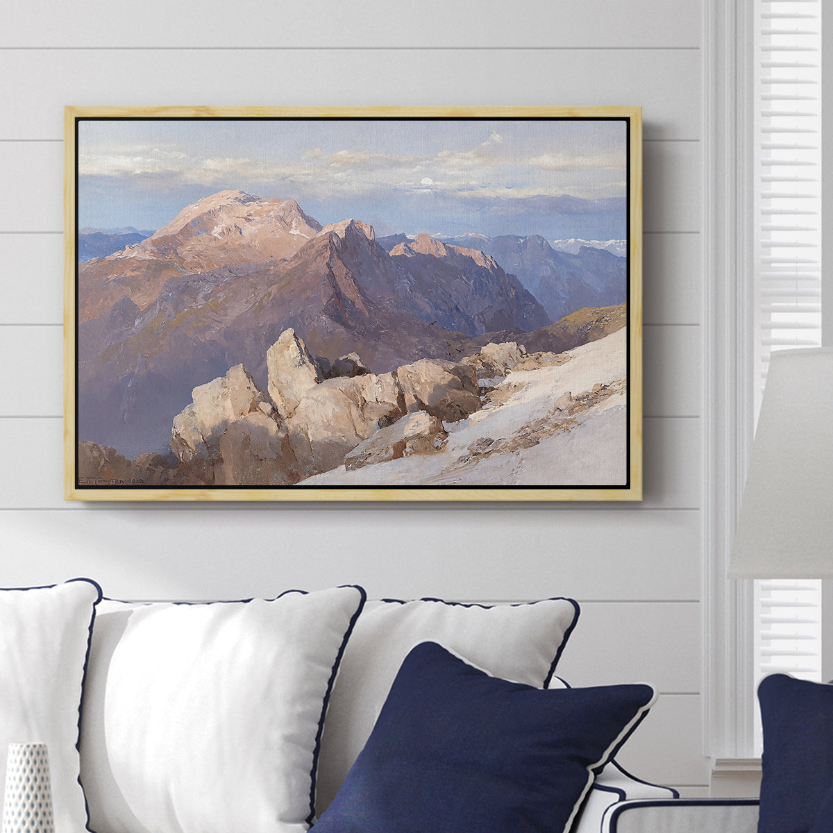Hoher Göll from Watzmann-Hocheck, 1919 by Edward Theodore Compton displayed above a sofa in a living room in a natural wood floater frame, featuring an alpine panorama showing layered peaks and valleys.