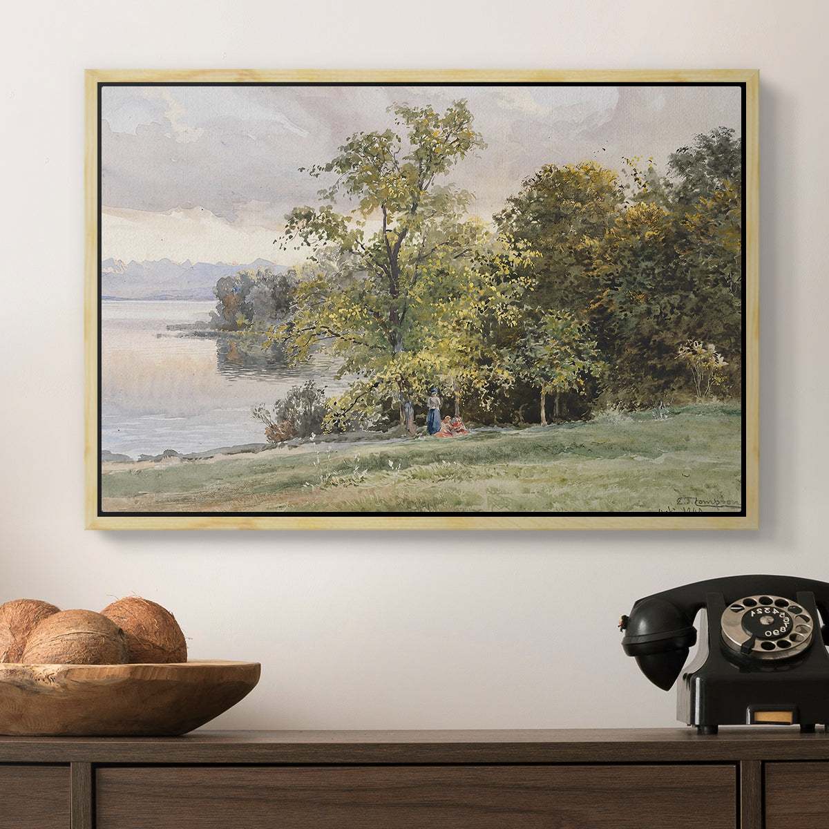 Landscape at Lake Starnberg, 1890 by Edward Theodore Compton in a natural wood floater framed canvas displayed above a console table in a hallway, featuring a tranquil lakeside view with soft atmospheric tones.