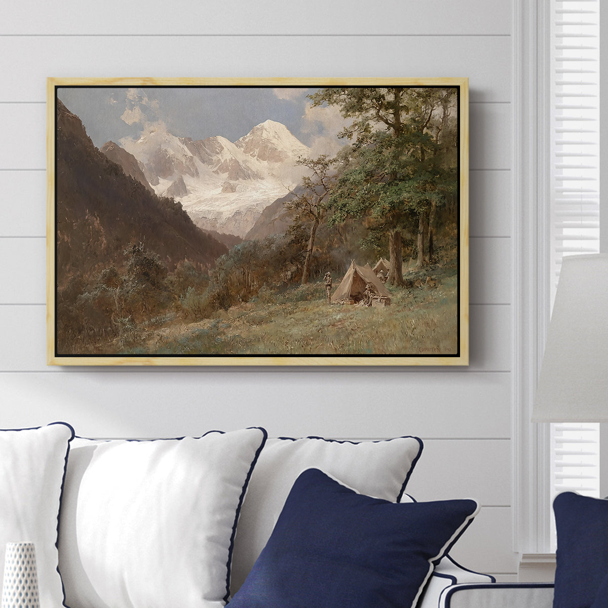 Landscape in the Caucasus, c. 1921 by Edward Theodore Compton displayed above a sofa in a living room in a natural wood floater frame, featuring an expansive view of Caucasus mountains under open sky.