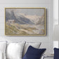 Shepherds (Pasterze), c. 1921 by Edward Theodore Compton displayed above a sofa in a living room in a natural wood floater frame, featuring a pastoral mountain scene with figures tending livestock.
