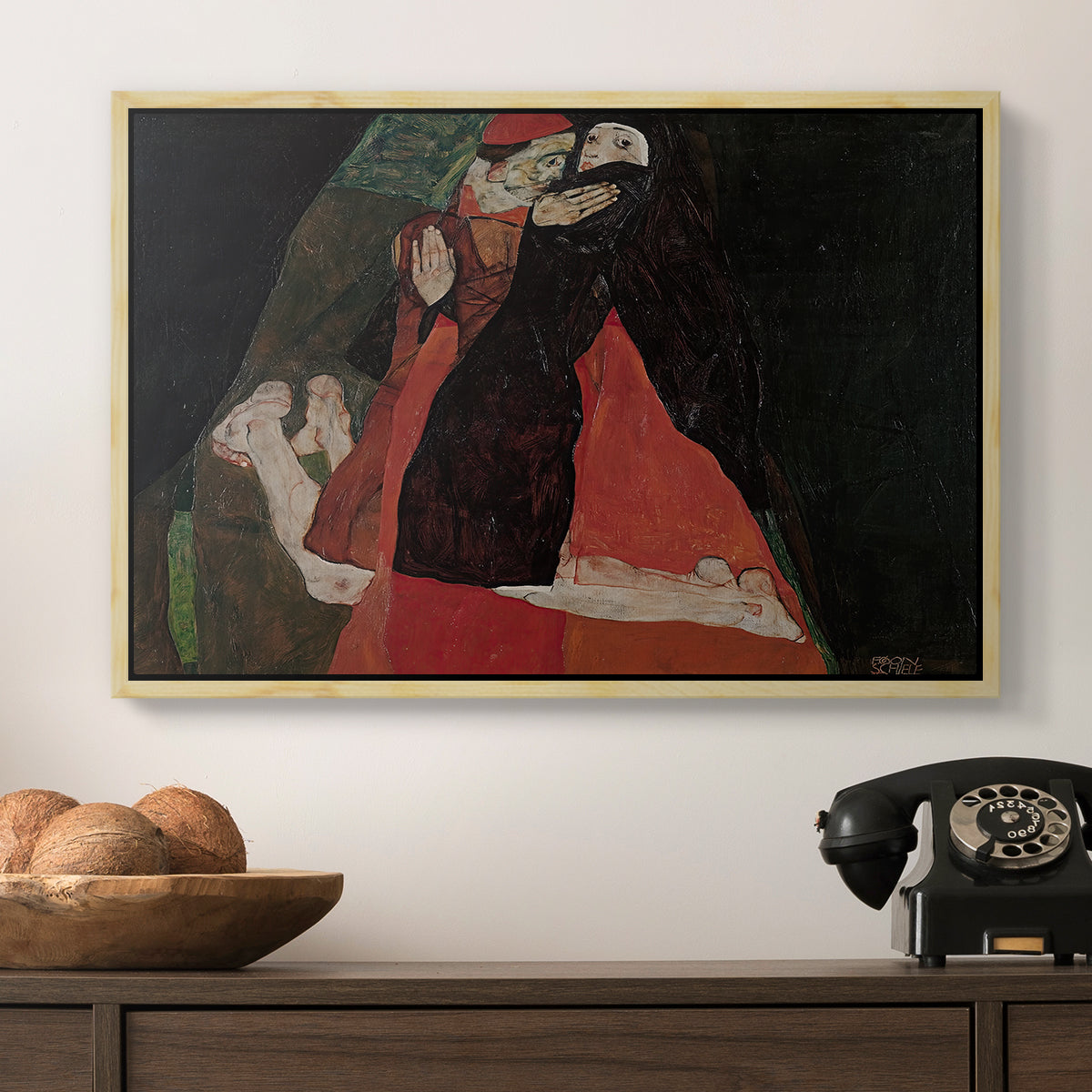 Cardinal and Nun (Caress), 1912 by Egon Schiele in a natural wood floater framed canvas displayed above a console table in a hallway, featuring an intimate scene with religious figures in modernist style.