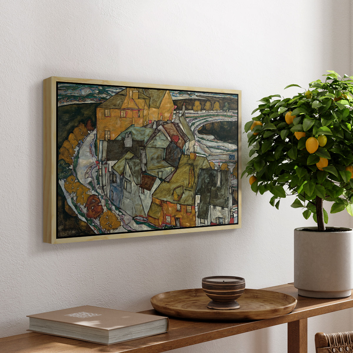 Crescent of Houses II (Island Town), 1915 by Egon Schiele, presented in a natural wood floater framed canvas featuring a curved row of colorful houses forming crescent shape along water, displayed above a hallway console table.