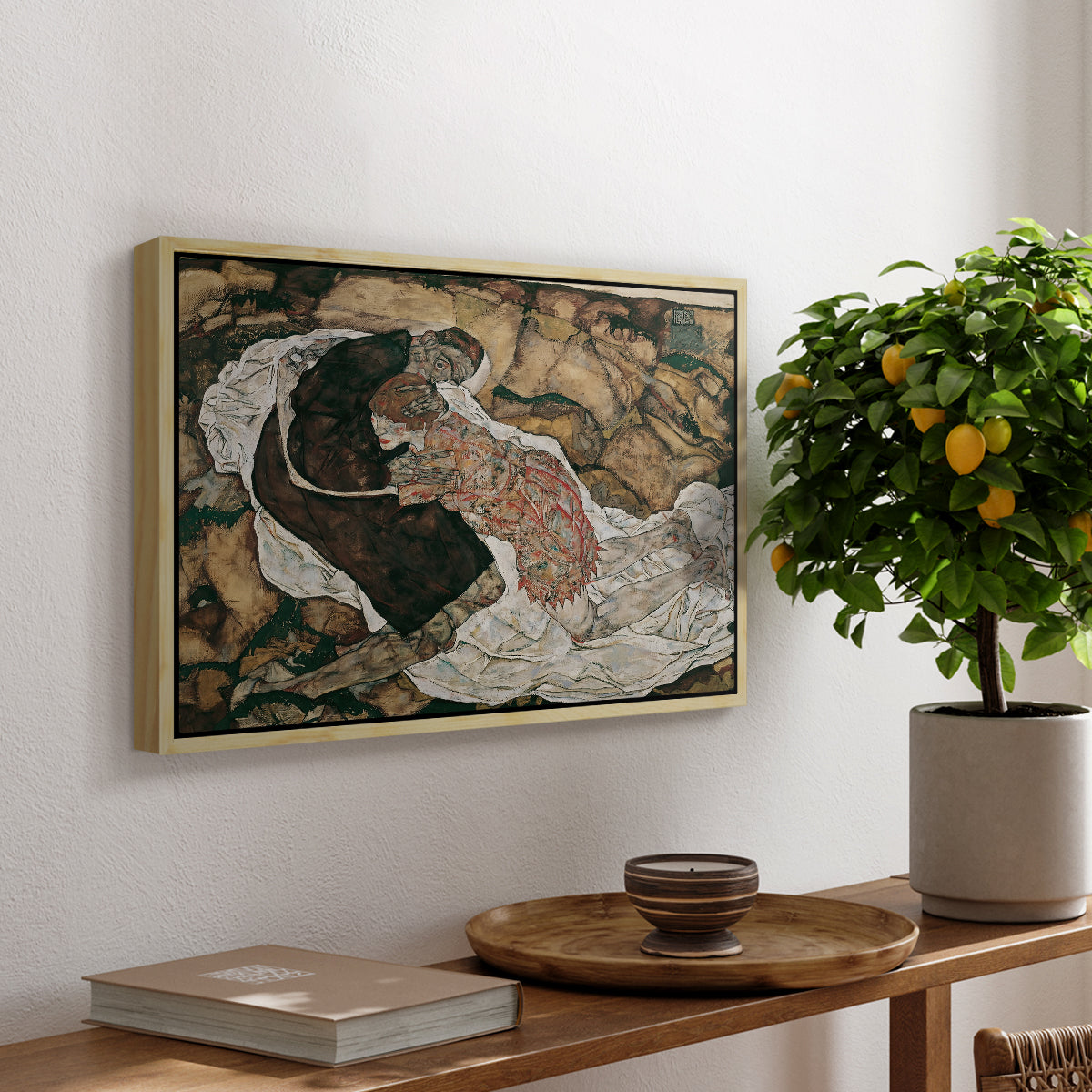 Death and the Maiden, 1915 by Egon Schiele, presented in a natural wood floater framed canvas featuring intertwined figures representing death and woman in emotional embrace, displayed above a hallway console table.