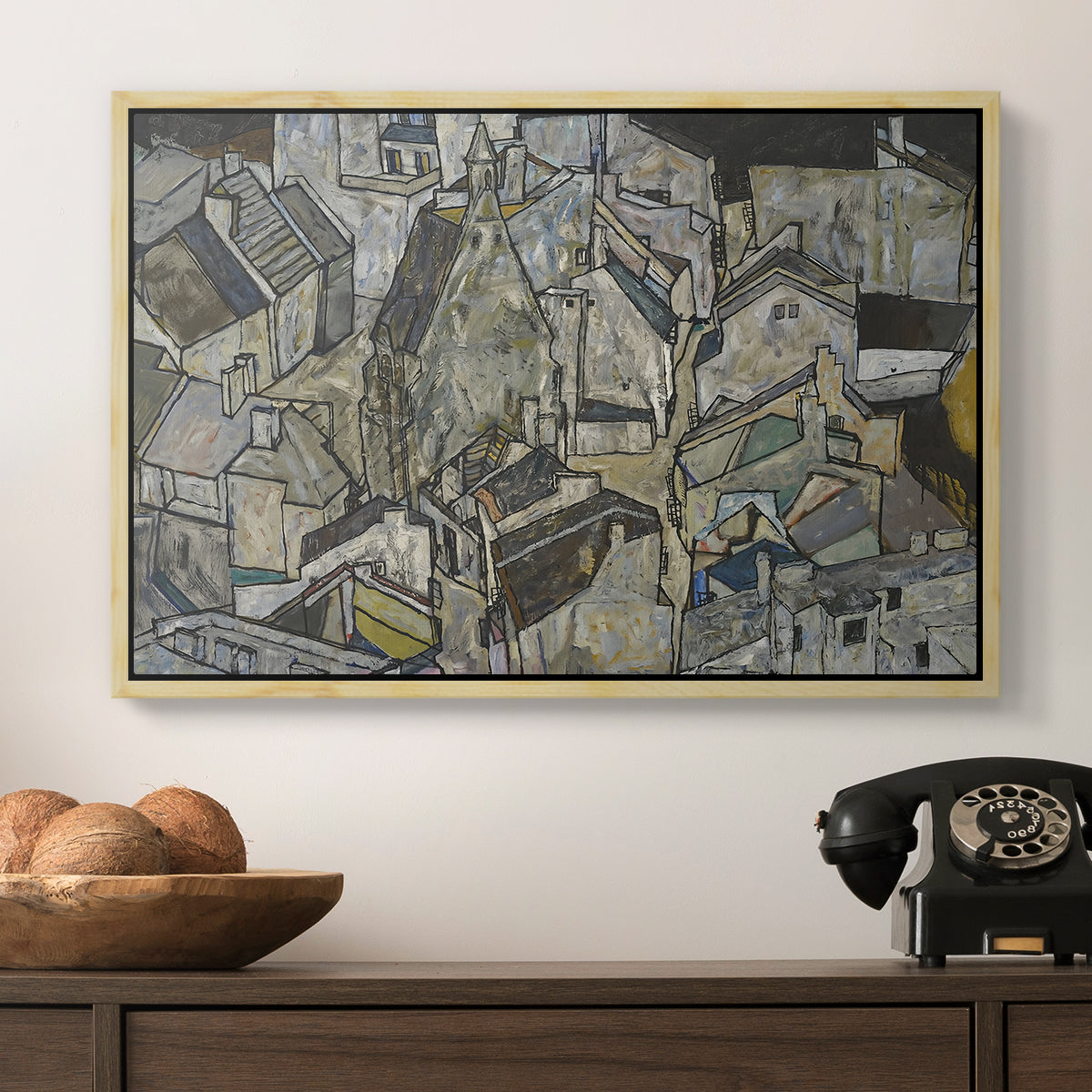 Mödling II, 1918 by Egon Schiele in a natural wood floater framed canvas displayed above a console table in a hallway, featuring a stylized urban composition with geometric structures and muted tones.