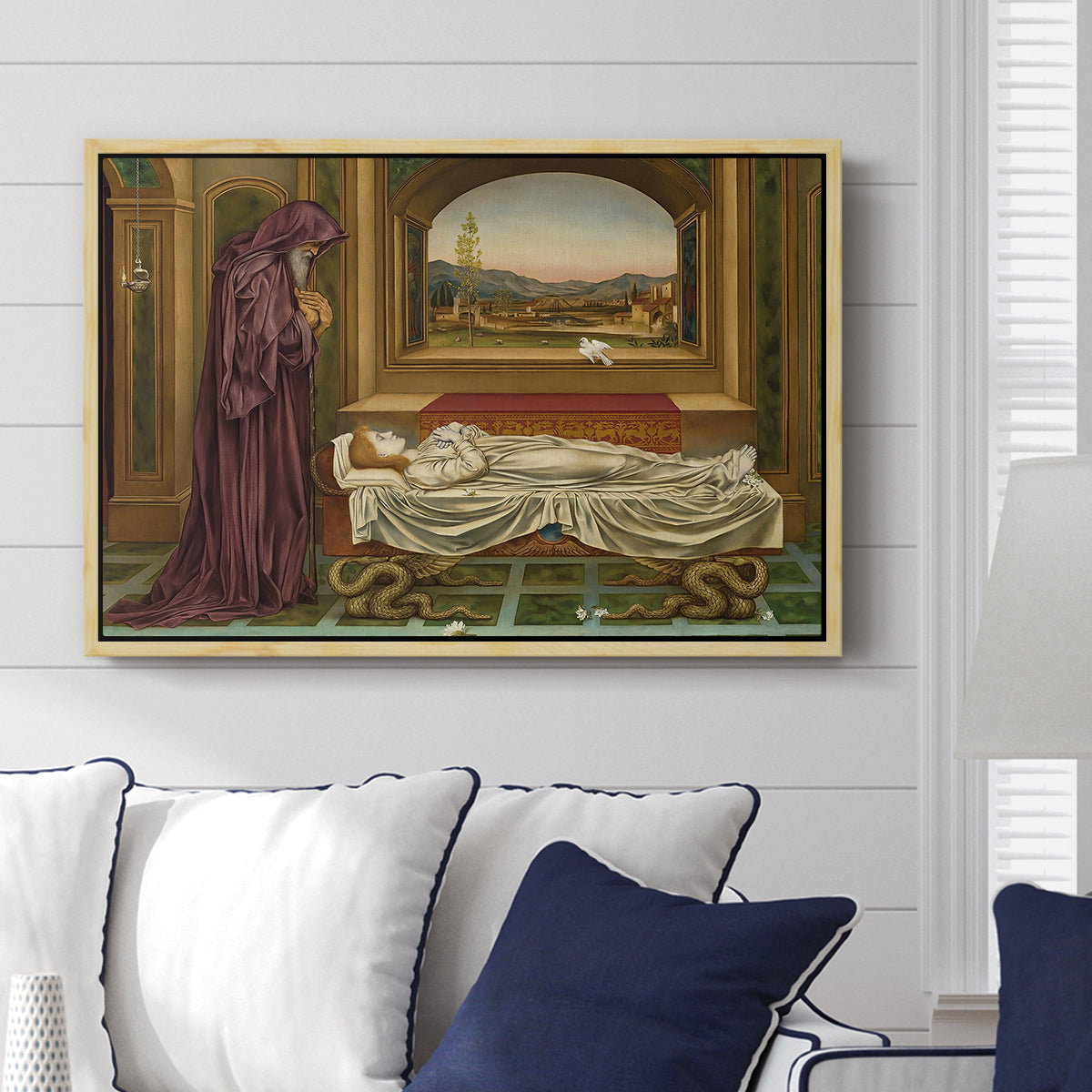 The Wandering Jew: Whom the Gods Love Die Young, 1888 by Evelyn De Morgan displayed above a sofa in a living room in a natural wood floater frame, featuring a symbolic portrait of wandering figure in quiet architectural setting.