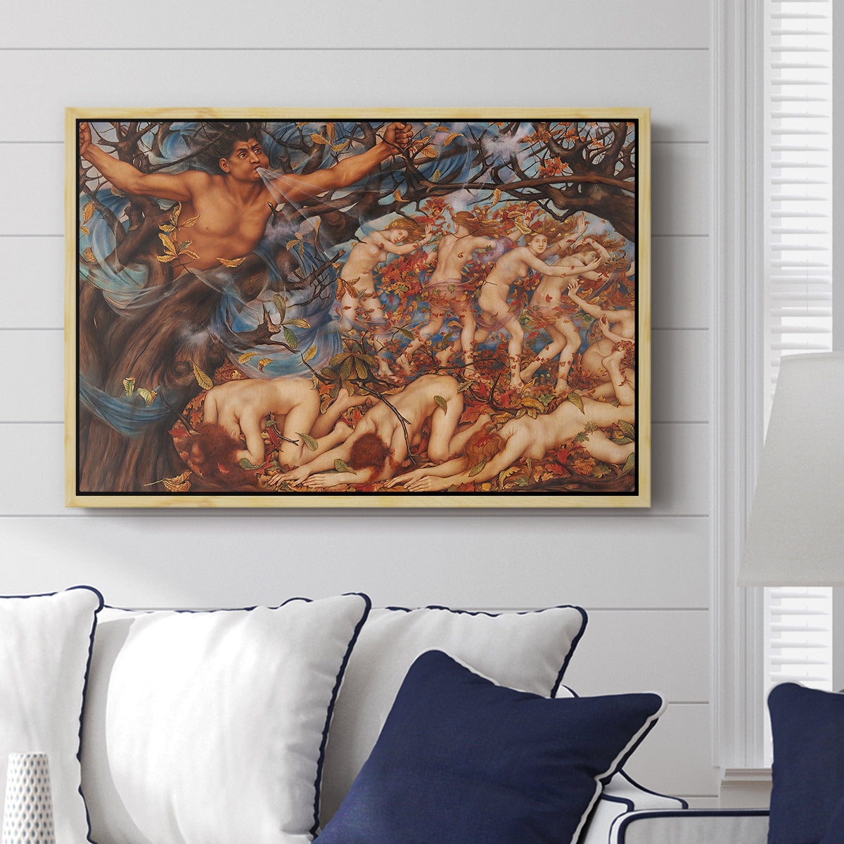 Boreas and the Fallen Leaves, c. 1910-1914 by Evelyn De Morgan displayed above a sofa in a living room in a natural wood floater frame, featuring a mythological scene of wind god Boreas moving through autumn leaves.