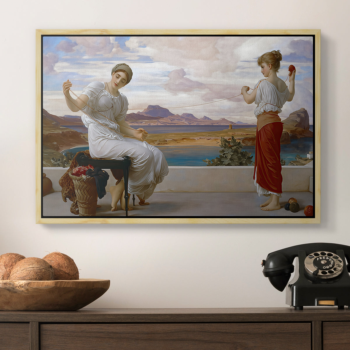 Winding the Skein, c. 1878 by Frederic Leighton in a natural wood floater framed canvas displayed above a console table in a hallway, featuring an elegant composition of women performing domestic task.