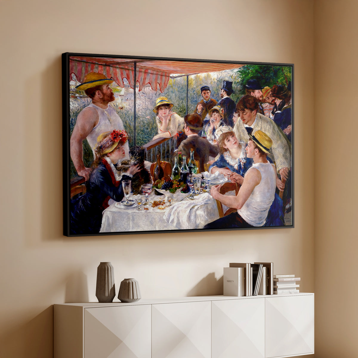 Black floater framed canvas of Luncheon of the Boating Party (Le Déjeuner des canotiers), 1880-1881 by Pierre-Auguste Renoir, featuring a lively gathering of men and women eating and socializing at outdoor table above a console cabinet in a minimalist entryway.