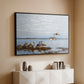 Black floater framed canvas of Greylag Geese (Grågäss), 1922 by Bruno Liljefors, featuring birds standing and resting along shoreline with soft grass and water above a console cabinet in a minimalist entryway.