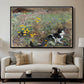 Cat on a Flowery Meadow, 1887 by Bruno Liljefors displayed in a black floater framed canvas above a sofa in a clean living room.