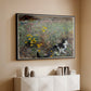 Black floater framed canvas of Cat on a Flowery Meadow, 1887 by Bruno Liljefors, featuring a small cat resting among colorful flowers in grassy field above a console cabinet in a minimalist entryway.