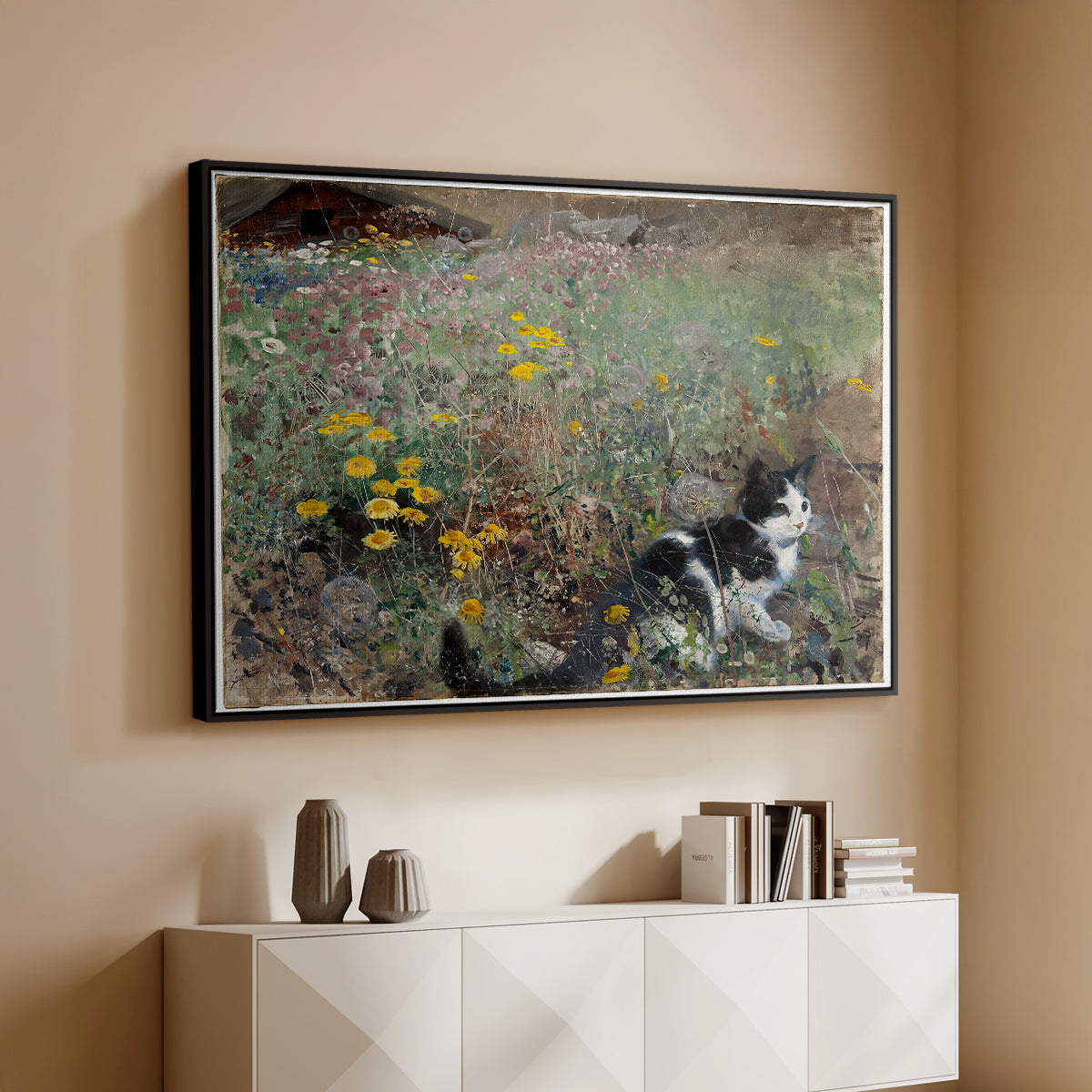 Black floater framed canvas of Cat on a Flowery Meadow, 1887 by Bruno Liljefors, featuring a small cat resting among colorful flowers in grassy field above a console cabinet in a minimalist entryway.