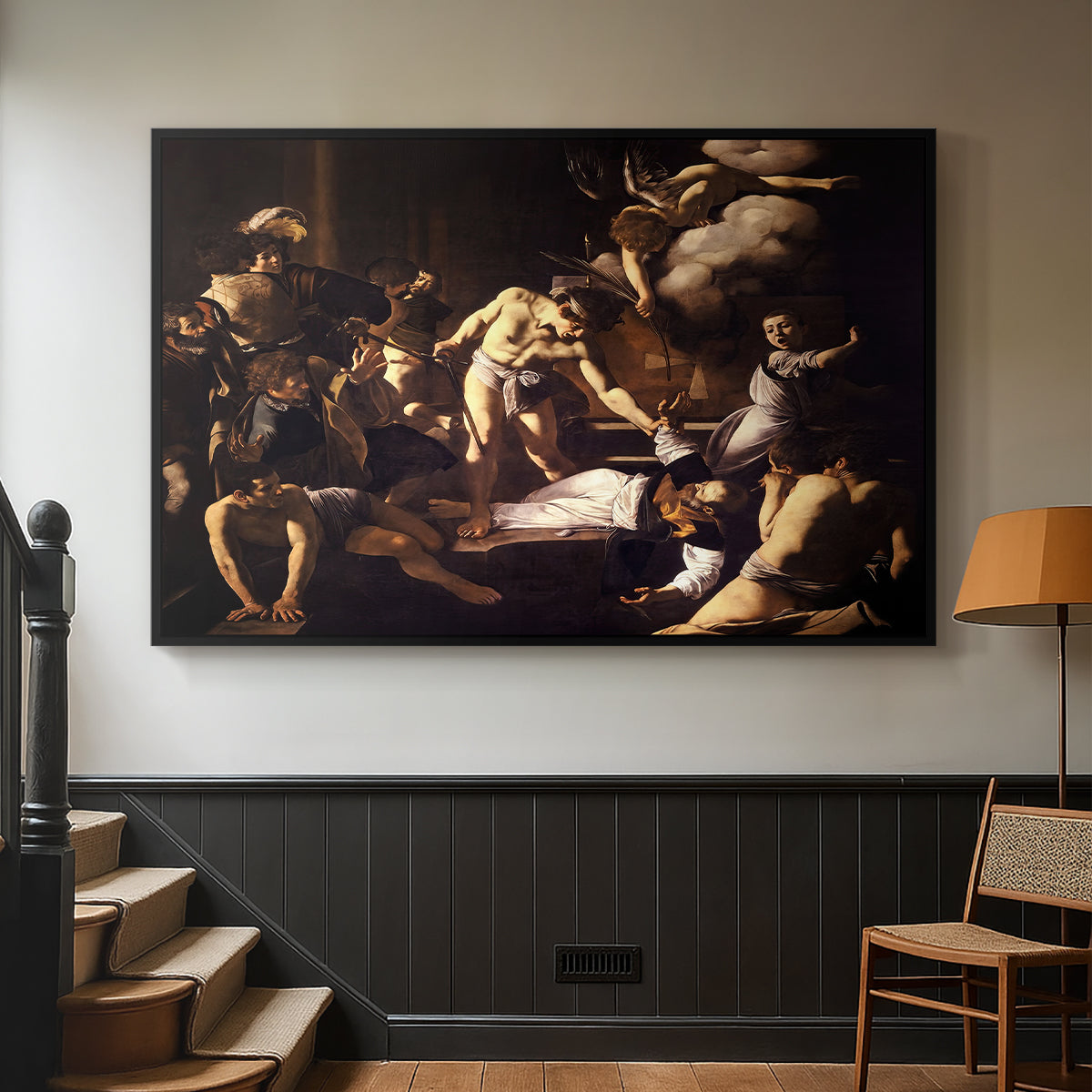 Black floater framed canvas featuring a Baroque composition of movement and emotion during martyrdom, displayed in a hallway near a staircase.