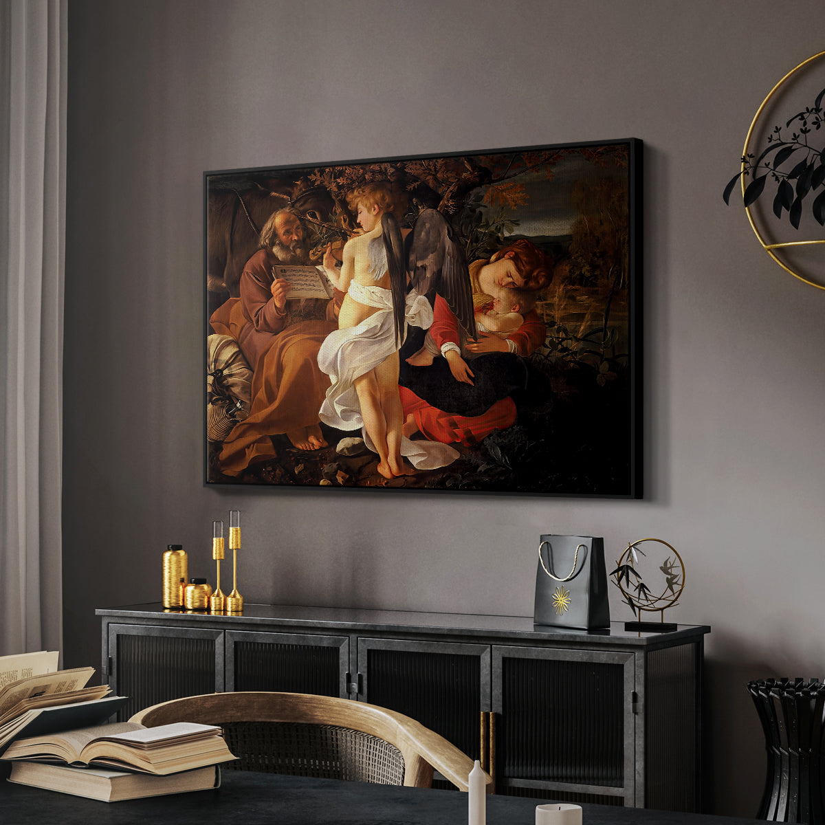 Rest on the Flight into Egypt, c. 1597 by Caravaggio in a black floater framed canvas featuring a peaceful religious moment with figures reclining in natural setting, displayed above a desk in a dark home office interior.