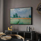 The Wheat Field (Champ de Blé), 1881 by Claude Monet in a black floater framed canvas featuring an agricultural landscape with tall wheat and distant horizon, displayed above a desk in a dark home office interior.