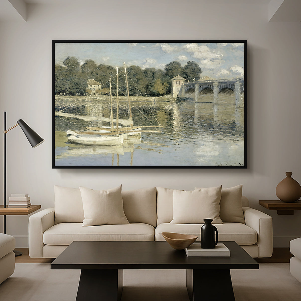 The Bridge at Argenteuil, 1874 by Claude Monet as a black floater framed canvas featuring a bridge spanning river with sailboats and reflections in water, displayed above a sofa in a modern living room.