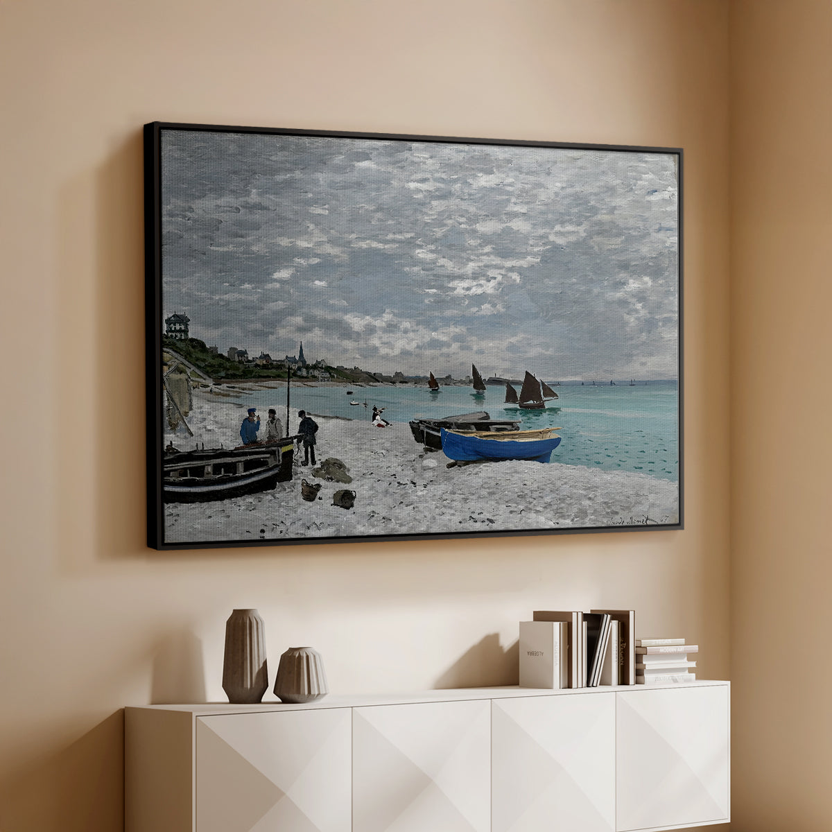 Black floater framed canvas of The Beach at Sainte-Adresse, 1867 by Claude Monet, featuring a lively beach scene with people overlooking water and ships above a console cabinet in a minimalist entryway.