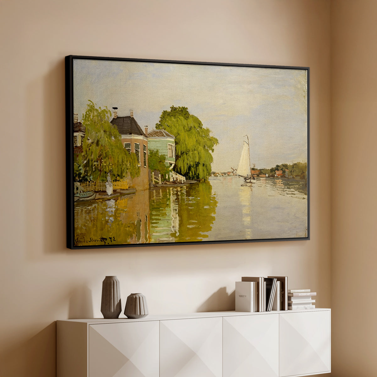 Black floater framed canvas of Houses on the Achterzaan, 1871 by Claude Monet, featuring riverside homes with trees and mirrored reflections in water above a console cabinet in a minimalist entryway.