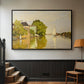 Black floater framed canvas featuring a peaceful village scene with houses bordering water, displayed in a hallway near a staircase.