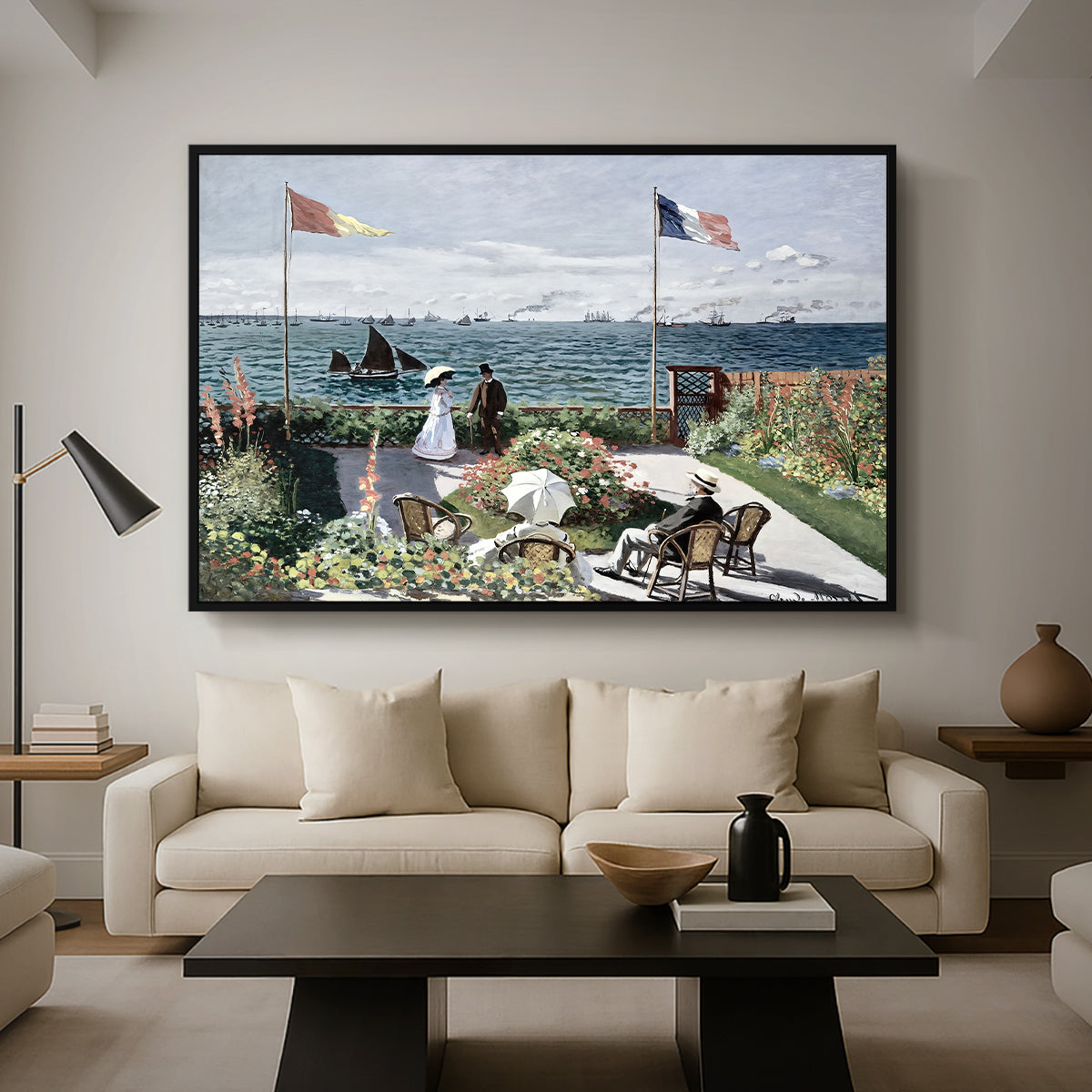Garden at Sainte-Adresse, 1867 by Claude Monet as a black floater framed canvas featuring a seaside garden with flowers, flags, and figures overlooking the water, displayed above a sofa in a modern living room.