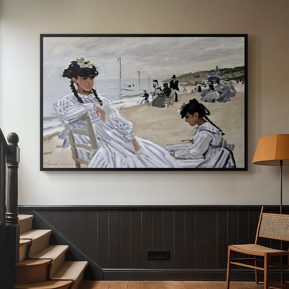 Black floater framed canvas featuring a coastal leisure scene with figures looking out to sea, displayed in a hallway near a staircase.