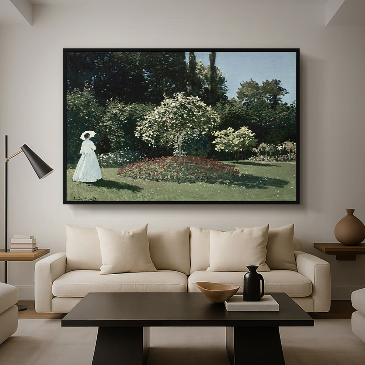 Woman in the Garden, Sainte-Adresse, 1867 by Claude Monet as a black floater framed canvas featuring a woman standing in garden surrounded by flowers and greenery, displayed above a sofa in a modern living room.