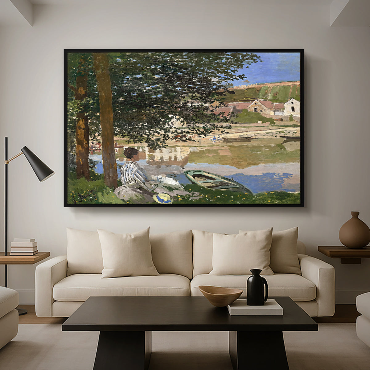 On the Bank of the Seine, Bennecourt, 1868 by Claude Monet as a black floater framed canvas featuring a woman and child seated along riverbank beneath trees in soft daylight, displayed above a sofa in a modern living room.