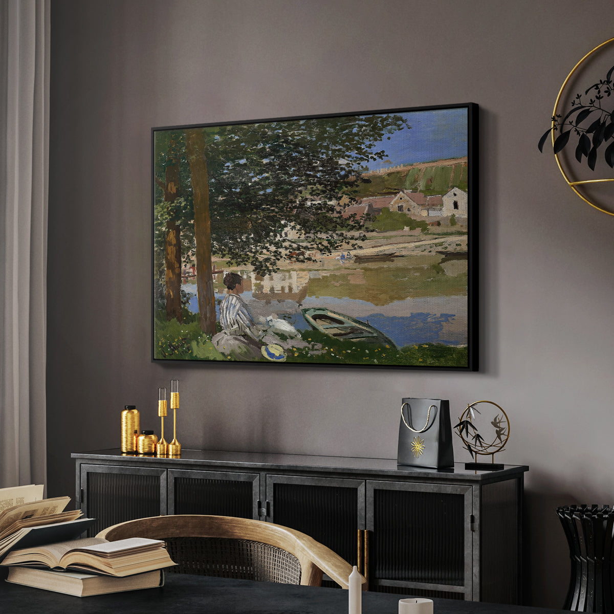 On the Bank of the Seine, Bennecourt, 1868 by Claude Monet in a black floater framed canvas featuring an impressionist landscape with people relaxing along the Seine, displayed above a desk in a dark home office interior.