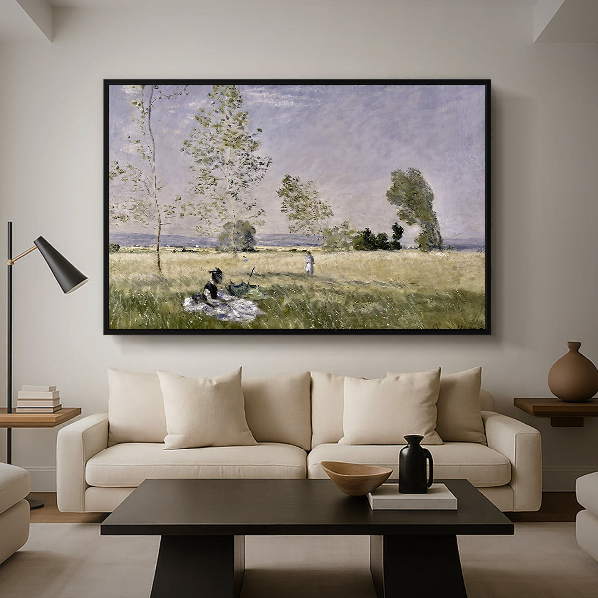 Summer (L'ete), 1874 by Claude Monet as a black floater framed canvas featuring a woman seated in grassy field beneath tree in bright summer landscape, displayed above a sofa in a modern living room.