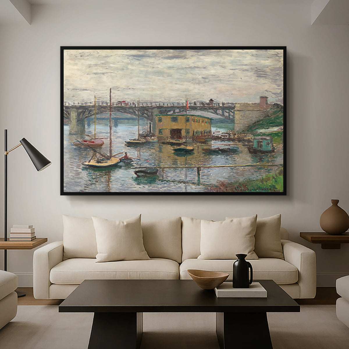 Bridge at Argenteuil on a Gray Day, c. 1876 by Claude Monet as a black floater framed canvas featuring a bridge crossing river under gray sky with muted reflections, displayed above a sofa in a modern living room.
