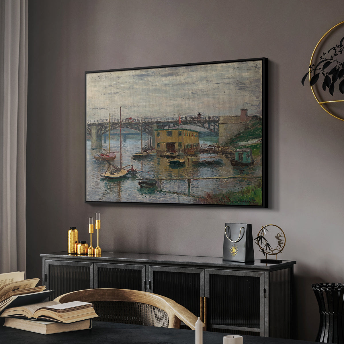 Bridge at Argenteuil on a Gray Day, c. 1876 by Claude Monet in a black floater framed canvas featuring a calm water scene with bridge fading into cloudy sky, displayed above a desk in a dark home office interior.