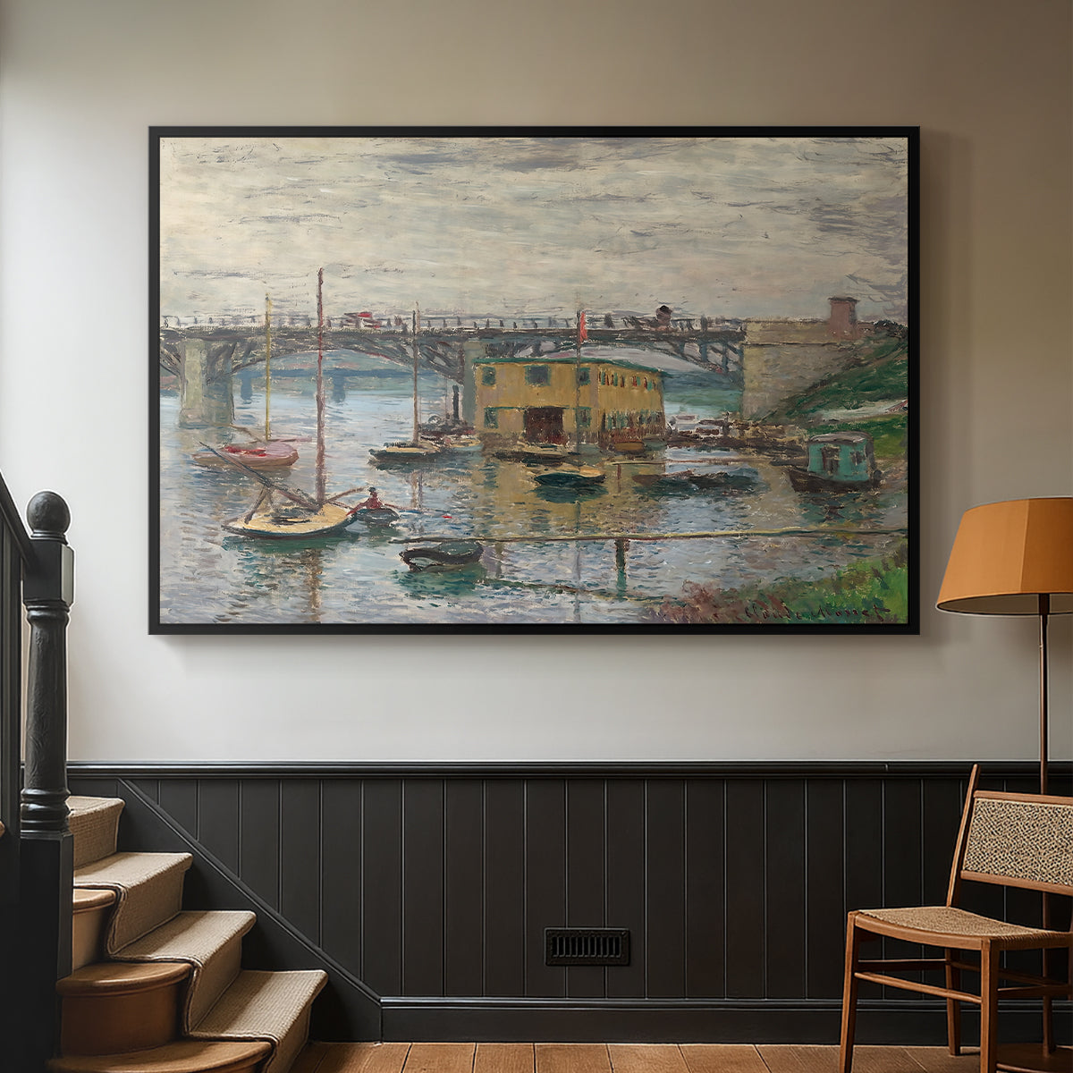 Black floater framed canvas featuring a subdued urban landscape with structure spanning river, displayed in a hallway near a staircase.