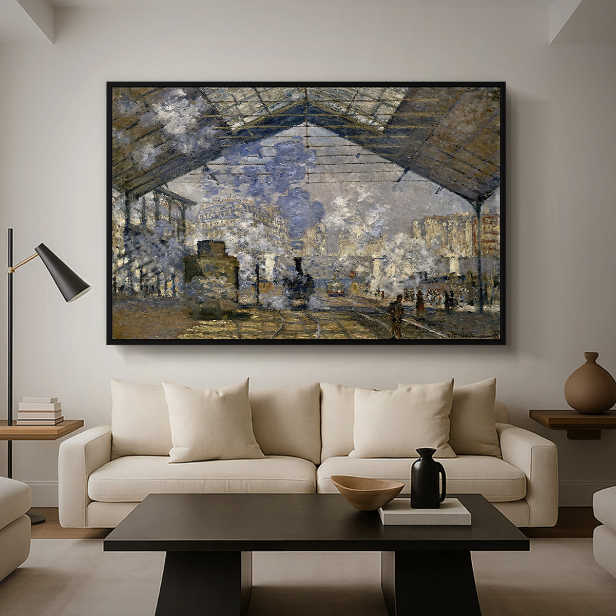 The Gare Saint-Lazare, 1877 by Claude Monet as a black floater framed canvas featuring a train station interior filled with steam and locomotives under iron structure, displayed above a sofa in a modern living room.
