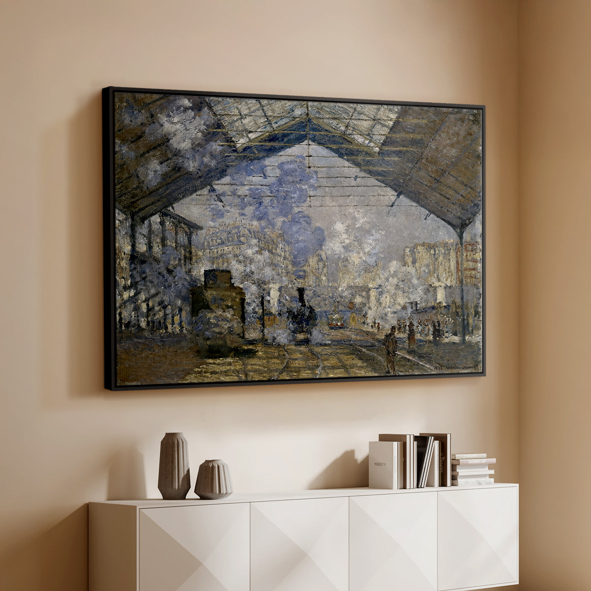Black floater framed canvas of The Gare Saint-Lazare, 1877 by Claude Monet, featuring an impressionist scene of trains and smoke inside busy railway station above a console cabinet in a minimalist entryway.