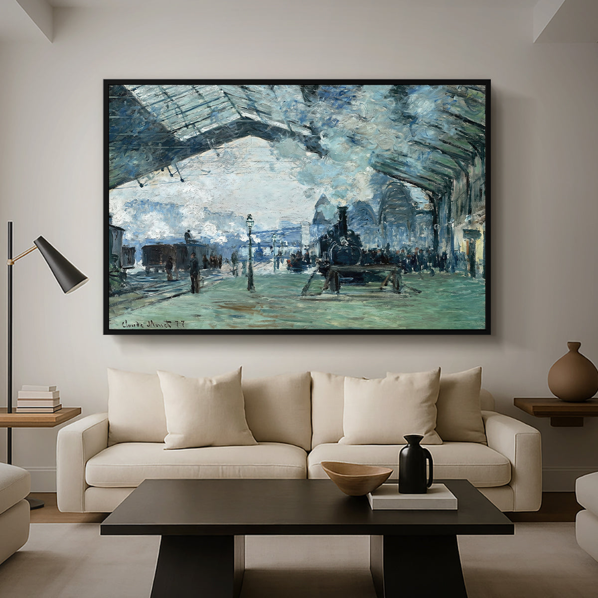 The Saint-Lazare Station, 1877 by Claude Monet as a black floater framed canvas featuring trains arriving under large arched station roof with billowing steam, displayed above a sofa in a modern living room.