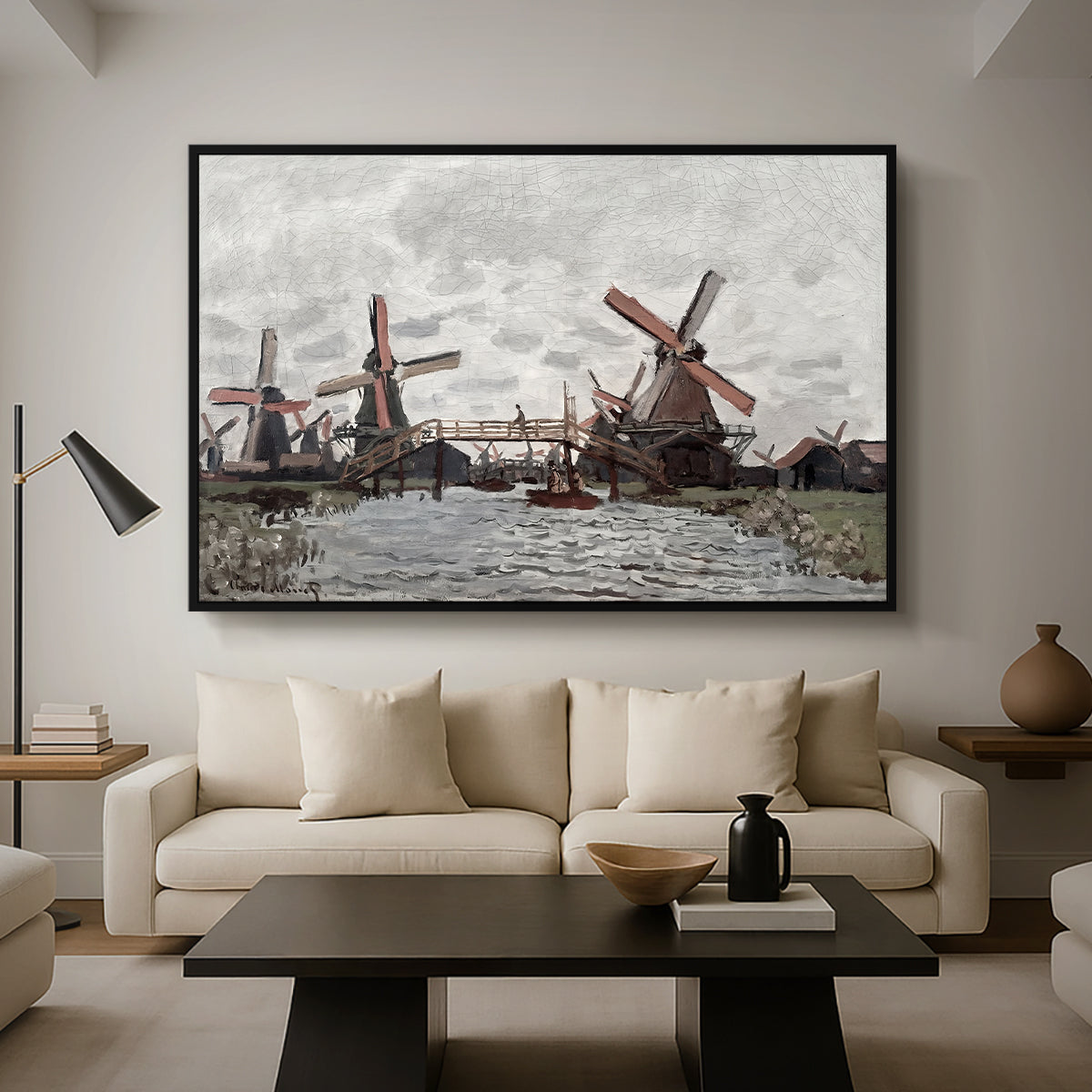Windmills near Zaandam, 1871 by Claude Monet as a black floater framed canvas featuring windmills standing beside water under open sky in rural landscape, displayed above a sofa in a modern living room.