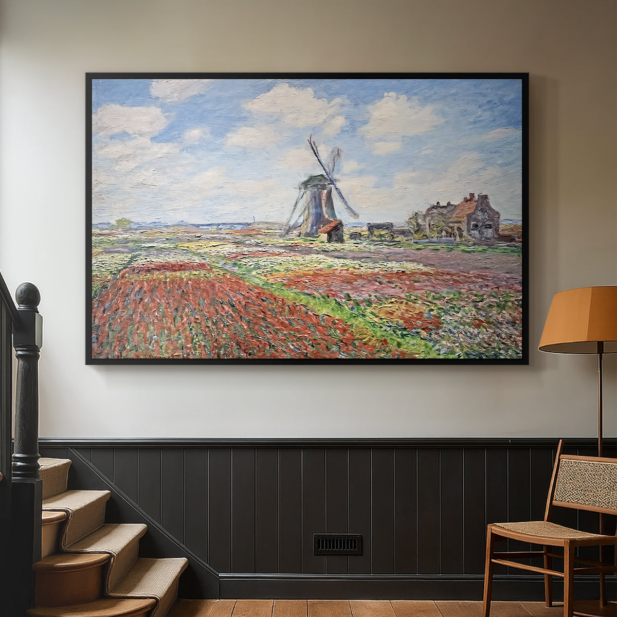 Black floater framed canvas featuring a rural scene with patterned rows of flowers and windmill, displayed in a hallway near a staircase.