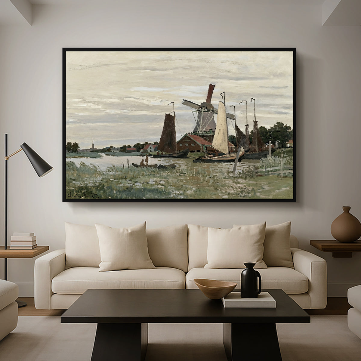 Windmill at Zaandam, 1871 by Claude Monet as a black floater framed canvas featuring a single windmill beside water with surrounding buildings and sky, displayed above a sofa in a modern living room.