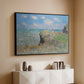 Black floater framed canvas of The Cliff Walk at Pourville, 1882 by Claude Monet, featuring an impressionist seaside landscape with people strolling above water above a console cabinet in a minimalist entryway.