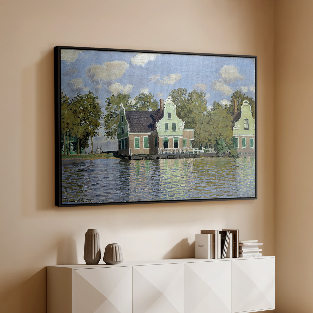 Black floater framed canvas of Houses on the Zaan River at Zaandam, 1871 by Claude Monet, featuring an impressionist riverside village with colorful buildings above a console cabinet in a minimalist entryway.