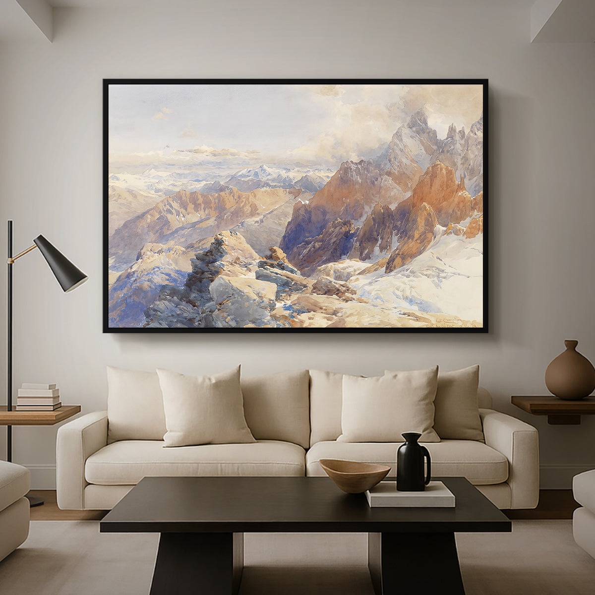Col du Géant, 1903 by Edward Theodore Compton as a black floater framed canvas featuring a mountain pass with snow-covered peaks and expansive alpine valley, displayed above a sofa in a modern living room.