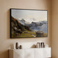 Black floater framed canvas of The Großglockner from the Prager Hut, 1890 by Edward Theodore Compton, featuring a mountain summit seen from elevated viewpoint with surrounding landscape above a console cabinet in a minimalist entryway.