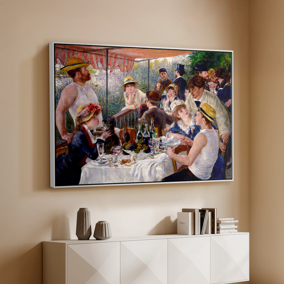 White floater framed canvas of Luncheon of the Boating Party (Le Déjeuner des canotiers), 1880-1881 by Pierre-Auguste Renoir, featuring a lively gathering of men and women eating and socializing at outdoor table above a console cabinet in a minimalist entryway.
