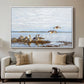 Greylag Geese (Grågäss), 1922 by Bruno Liljefors displayed in a white floater framed canvas above a sofa in a clean living room.