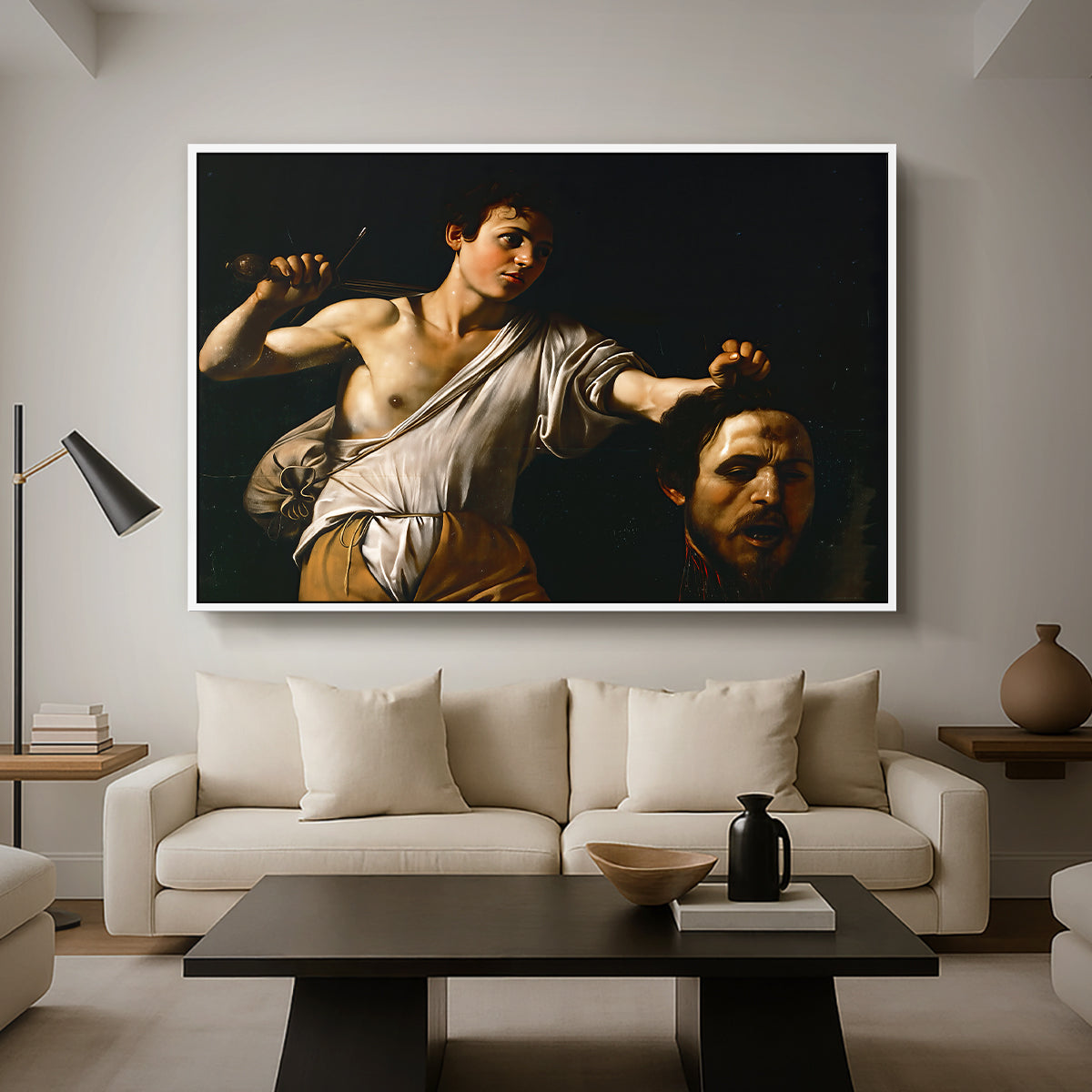 David with the Head of Goliath (Vienna Version), c. 1607 by Caravaggio as a white floater framed canvas featuring a young David holding the severed head of Goliath against a dark background, displayed above a sofa in a modern living room.