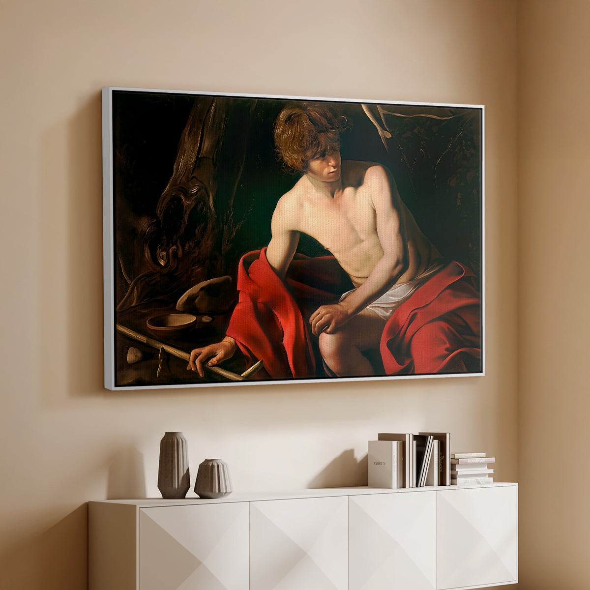 White floater framed canvas of Saint John the Baptist in the Wilderness, c. 1603-1604 by Caravaggio, featuring a solitary figure of Saint John resting in natural setting with soft light above a console cabinet in a minimalist entryway.