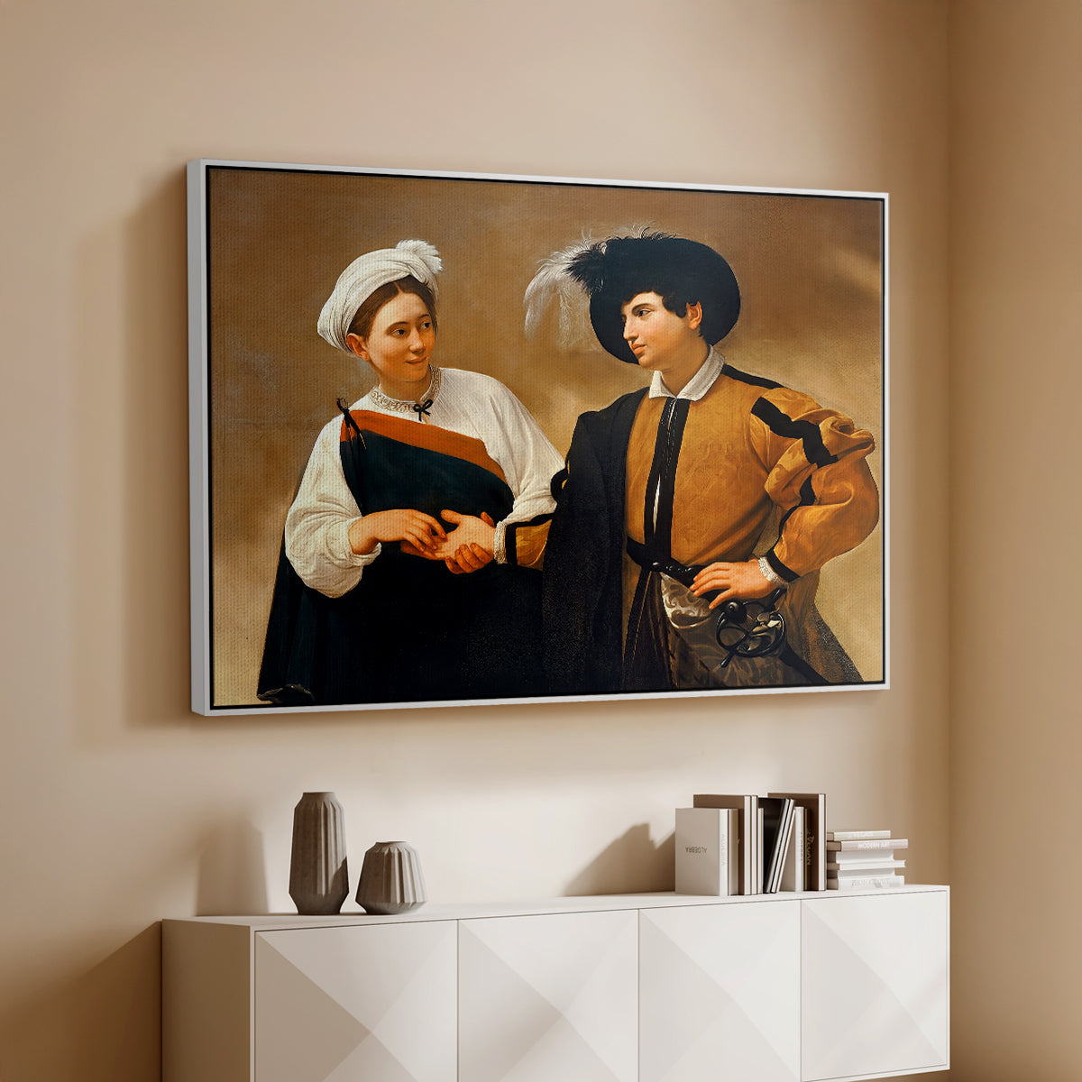 White floater framed canvas of The Fortune Teller (Capitoline Version), c. 1599 by Caravaggio, featuring a fortune teller tricking young man during palm reading above a console cabinet in a minimalist entryway.